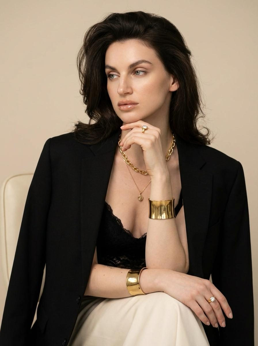 Thoughtful Woman in Elegant Gold Jewelry and Blazer