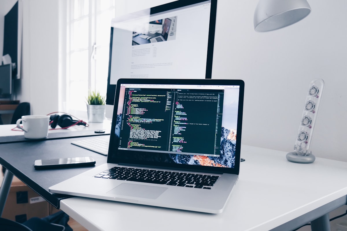 Laptop with code and workflow tools on desk for freelance AI design pipeline
